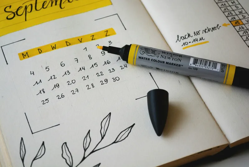 Calendrier mensuel dessiné à la main dans un carnet, annoté au marqueur